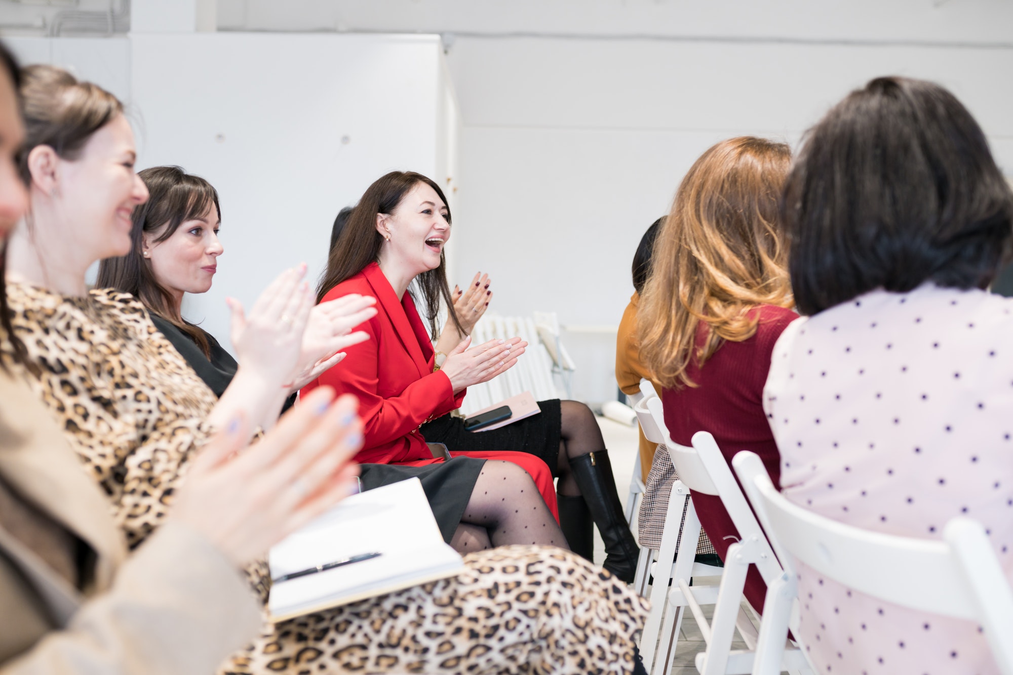 Home Women applauding speaker at group session, sitting in audience at training meeting